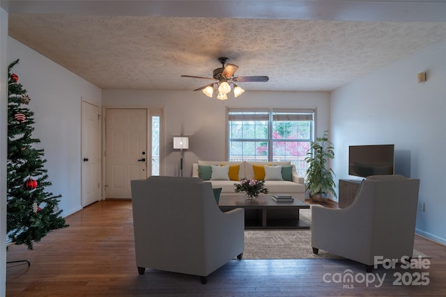 living room with ceiling fan, light hardwood / wood-style floors, and a textured ceiling