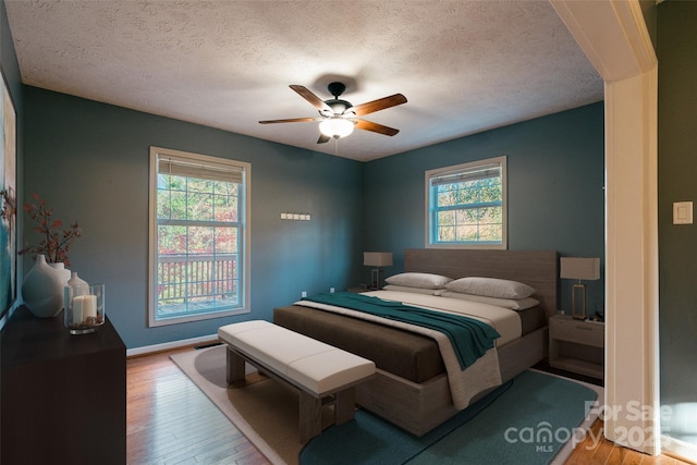 bedroom featuring wood-type flooring, a textured ceiling, and ceiling fan