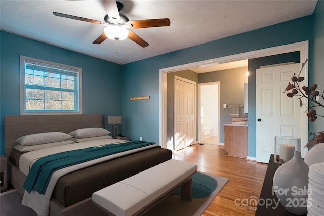 bedroom featuring hardwood / wood-style floors, ceiling fan, a textured ceiling, and connected bathroom