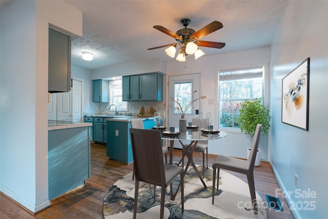 dining area with a healthy amount of sunlight, ceiling fan, dark wood-type flooring, and a textured ceiling