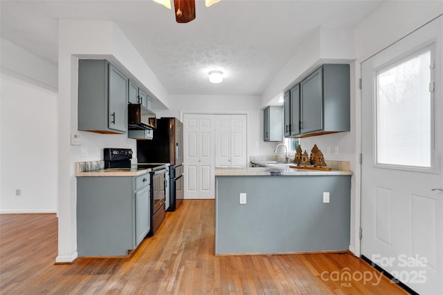 kitchen featuring gray cabinets, light wood-type flooring, a textured ceiling, and black / electric stove