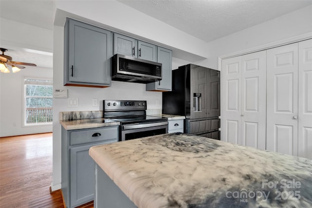 kitchen featuring ceiling fan, dark hardwood / wood-style floors, a textured ceiling, gray cabinets, and appliances with stainless steel finishes