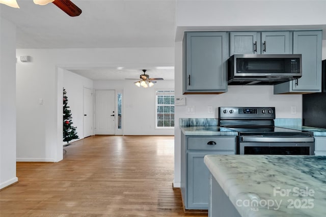 kitchen with appliances with stainless steel finishes, light hardwood / wood-style floors, ceiling fan, and gray cabinetry