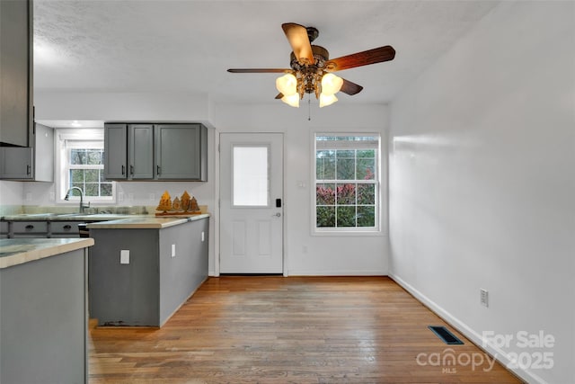 kitchen featuring gray cabinetry, ceiling fan, light hardwood / wood-style floors, and a textured ceiling