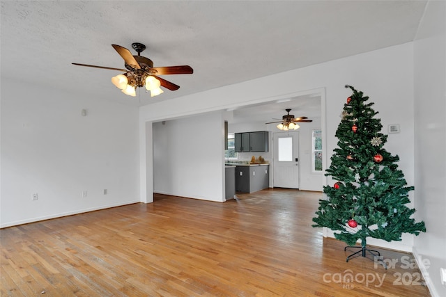 unfurnished living room featuring ceiling fan, light hardwood / wood-style floors, and a textured ceiling