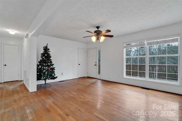 empty room with ceiling fan, light hardwood / wood-style floors, and a textured ceiling