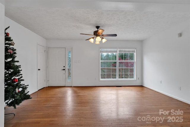 empty room featuring a textured ceiling, light hardwood / wood-style flooring, and ceiling fan