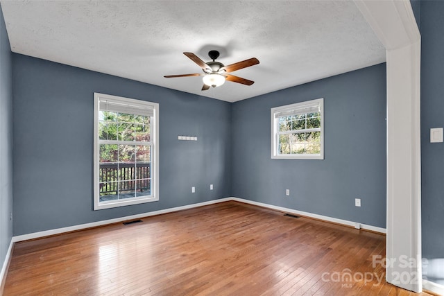 empty room with hardwood / wood-style floors, a healthy amount of sunlight, and a textured ceiling