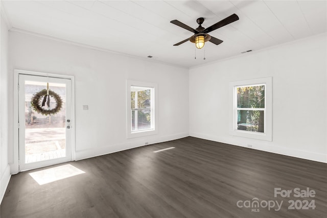 empty room with crown molding, a healthy amount of sunlight, and dark hardwood / wood-style floors