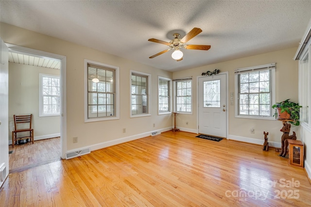 interior space with ceiling fan, light wood-type flooring, and a textured ceiling