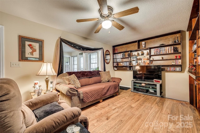 living room with ceiling fan, light hardwood / wood-style floors, and a textured ceiling