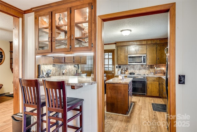 kitchen featuring a center island, backsplash, range with electric stovetop, light wood-type flooring, and a textured ceiling