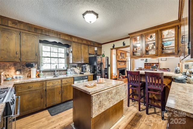 kitchen featuring light wood-type flooring, appliances with stainless steel finishes, a center island, and sink