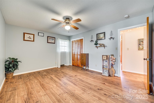 unfurnished room with a textured ceiling, light hardwood / wood-style flooring, and ceiling fan