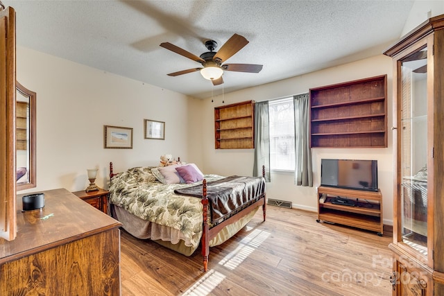 bedroom featuring light wood-type flooring, a textured ceiling, and ceiling fan