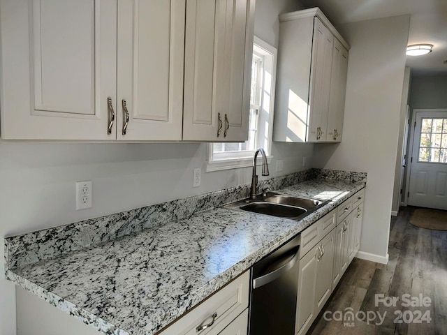 kitchen featuring dark wood-type flooring, white cabinets, sink, stainless steel dishwasher, and light stone counters