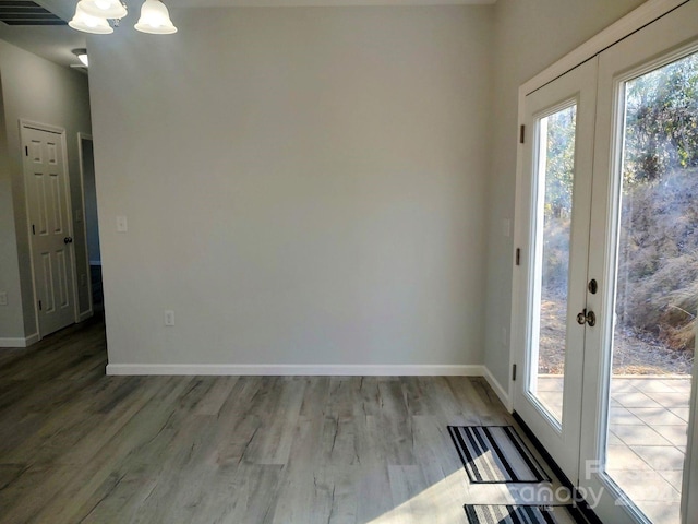 entryway with plenty of natural light, an inviting chandelier, and light hardwood / wood-style flooring