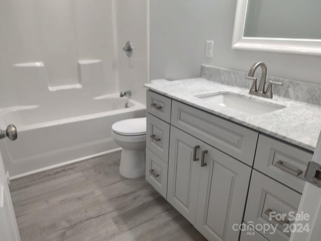 full bathroom with hardwood / wood-style floors, vanity, toilet, and shower / washtub combination