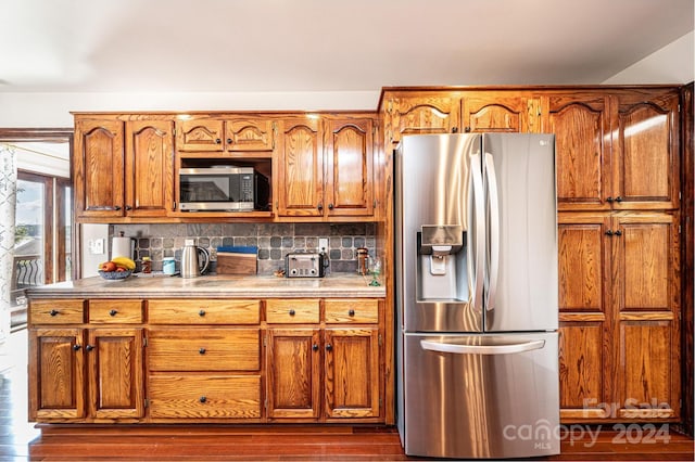 kitchen with decorative backsplash, appliances with stainless steel finishes, and dark hardwood / wood-style floors