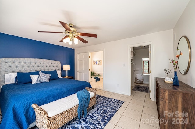 bedroom featuring light tile patterned floors, a walk in closet, ensuite bath, and ceiling fan