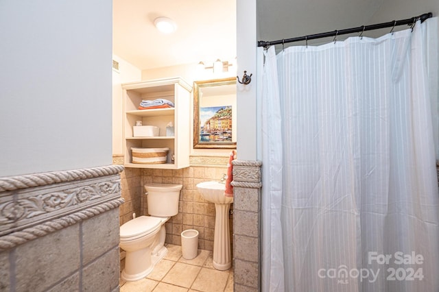 bathroom with tile patterned flooring, toilet, and tile walls