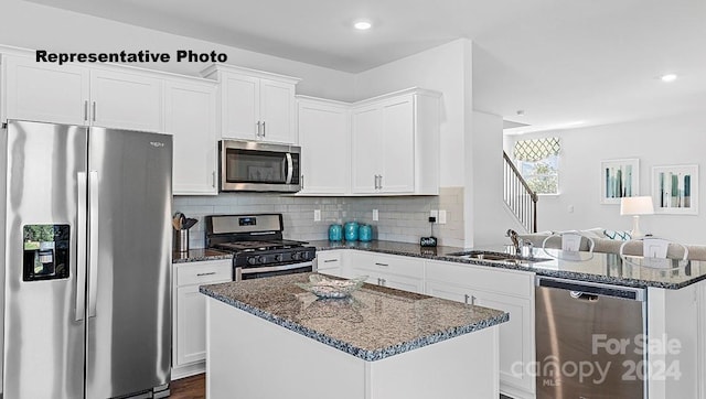 kitchen featuring white cabinetry, sink, dark stone countertops, a kitchen island, and appliances with stainless steel finishes