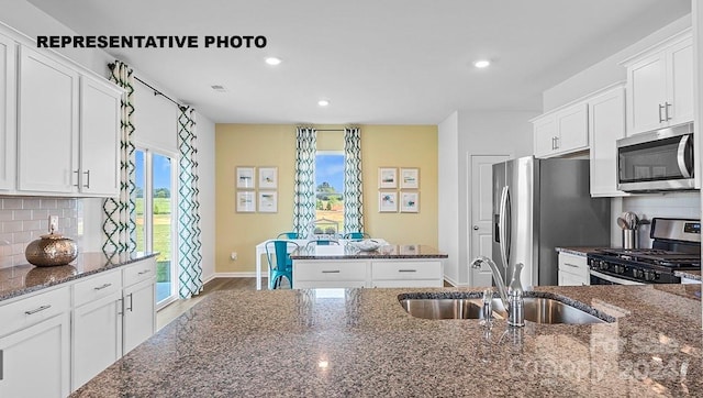 kitchen with sink, white cabinets, dark stone countertops, and stainless steel appliances