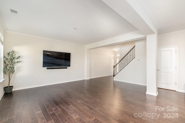 unfurnished living room featuring dark wood-type flooring and ornamental molding