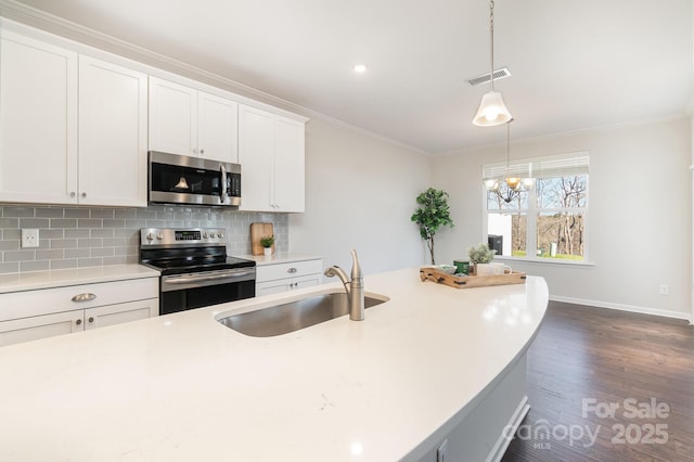 kitchen featuring appliances with stainless steel finishes, sink, hanging light fixtures, and white cabinets