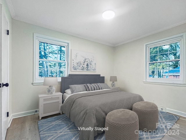 bedroom featuring multiple windows, ornamental molding, and hardwood / wood-style flooring