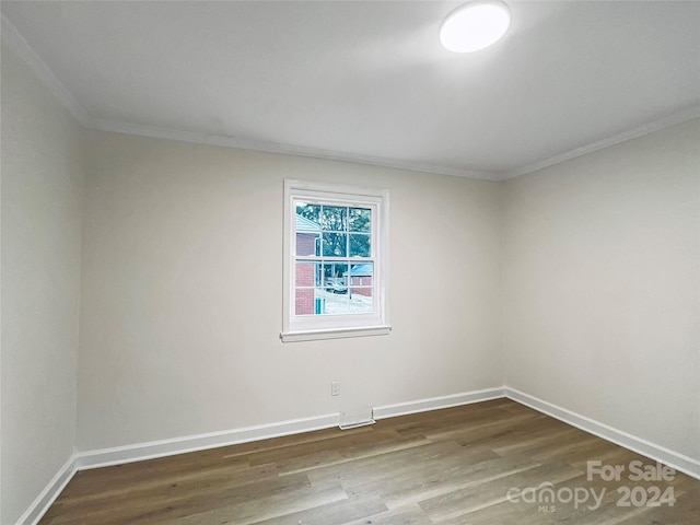 empty room featuring hardwood / wood-style flooring and crown molding