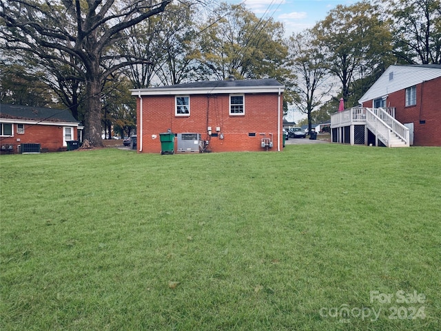 rear view of house featuring a lawn, central AC unit, and a deck