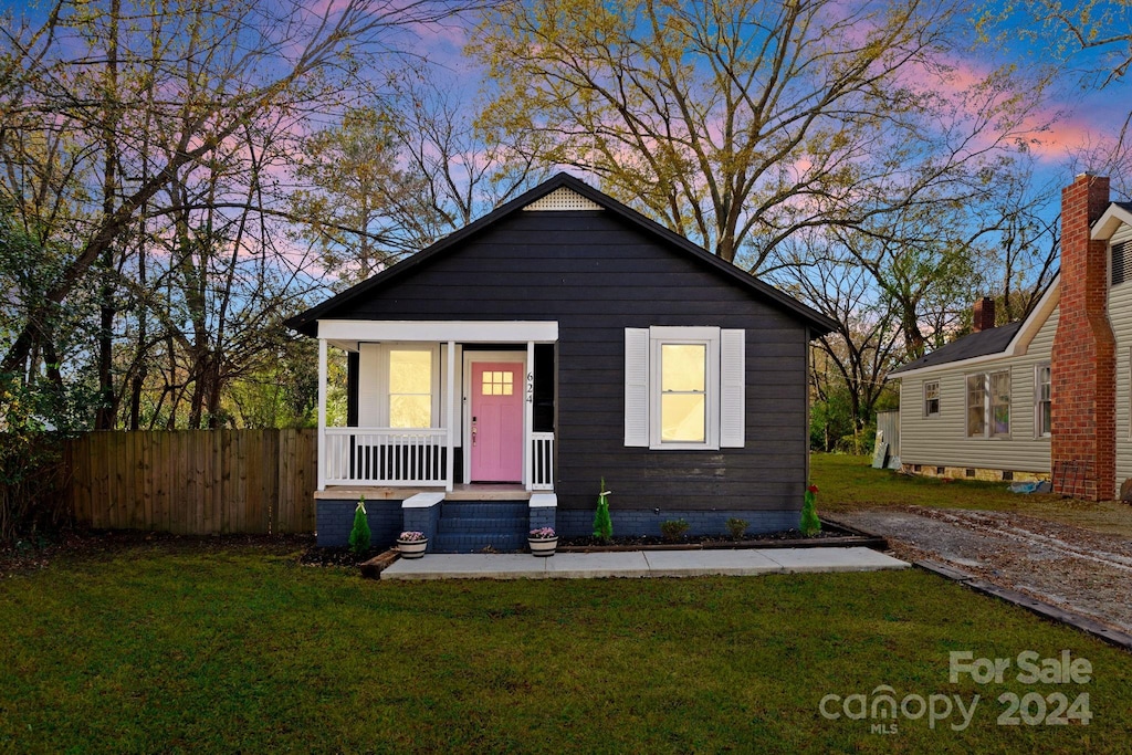 bungalow-style house with covered porch and a yard