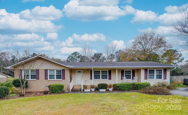 ranch-style home featuring covered porch and a front lawn