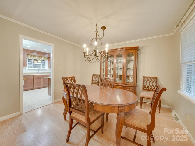 dining area featuring crown molding, sink, a chandelier, and light wood-type flooring