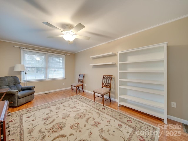 living area with wood-type flooring, ceiling fan, and ornamental molding