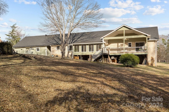 back of house featuring a sunroom, ceiling fan, a wooden deck, and a lawn