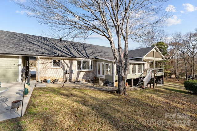 rear view of property featuring a lawn and a sunroom