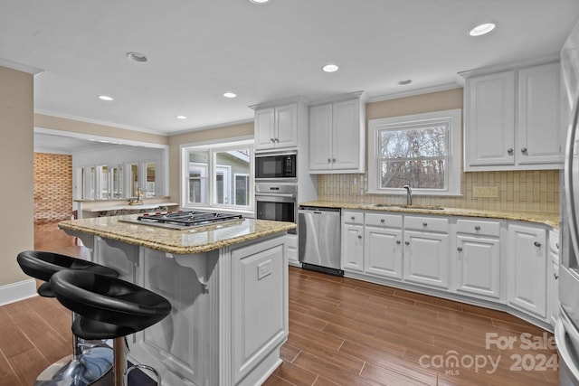 kitchen featuring appliances with stainless steel finishes, tasteful backsplash, a breakfast bar, sink, and white cabinets