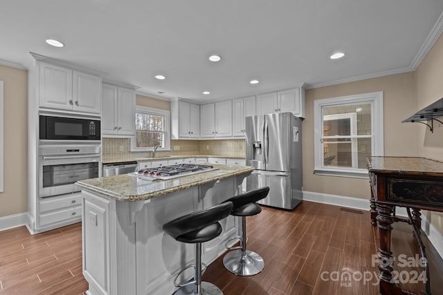 kitchen featuring hardwood / wood-style floors, crown molding, sink, appliances with stainless steel finishes, and white cabinetry