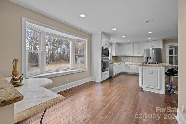 kitchen featuring appliances with stainless steel finishes, a breakfast bar, white cabinets, dark hardwood / wood-style floors, and a kitchen island