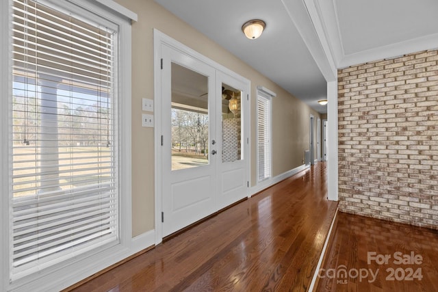 foyer with crown molding, dark wood-type flooring, and brick wall