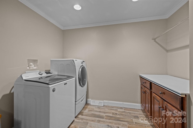 laundry room featuring crown molding, light hardwood / wood-style flooring, cabinets, and washer and dryer