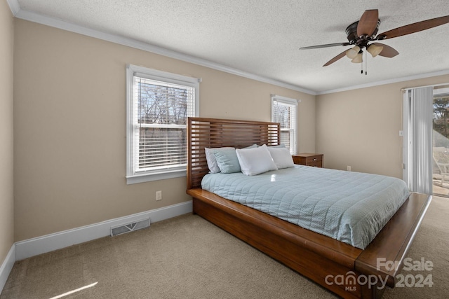 bedroom featuring multiple windows, ceiling fan, a textured ceiling, and ornamental molding