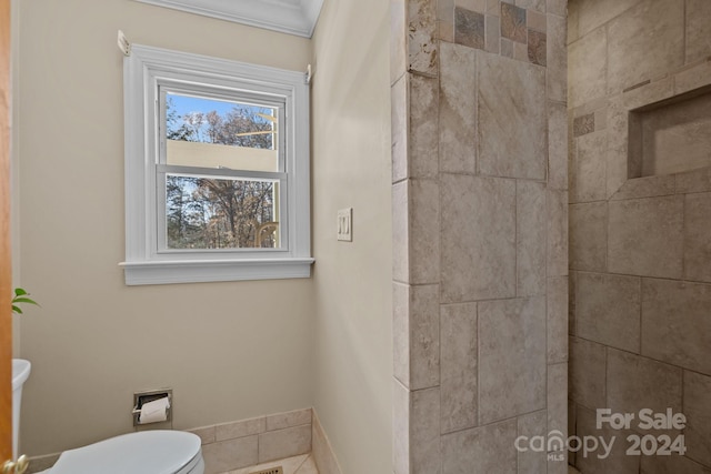 bathroom featuring tiled shower and toilet