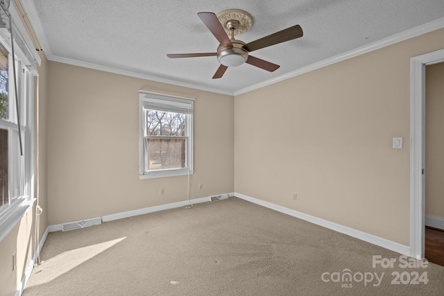 empty room with ceiling fan, light colored carpet, a textured ceiling, and ornamental molding