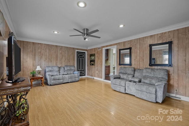 living room featuring wood walls, hardwood / wood-style floors, ceiling fan, and ornamental molding