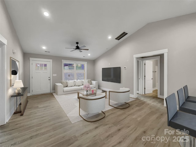 living room with ceiling fan, light hardwood / wood-style flooring, and vaulted ceiling