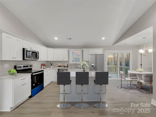 kitchen with a center island, vaulted ceiling, stainless steel appliances, and white cabinetry