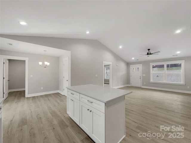 kitchen with white cabinets, ceiling fan with notable chandelier, hanging light fixtures, vaulted ceiling, and light wood-type flooring